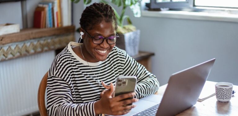lady on laptop and mobile happy because she is making tax savings