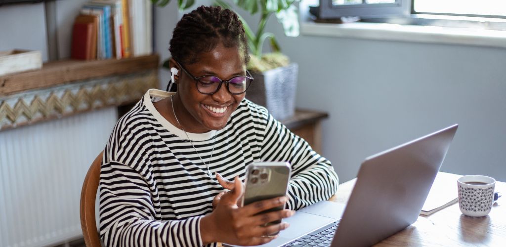 lady on laptop and mobile happy because she is making tax savings